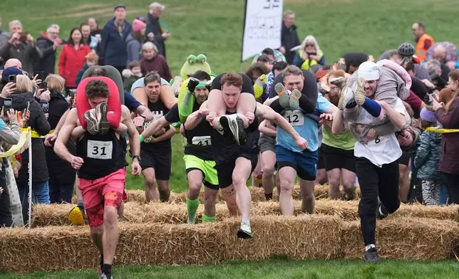 People take part in the annual UK Wife Carrying Race in Dorking, England, Sunday March 8, 2026. (Gareth Fuller/PA via AP)