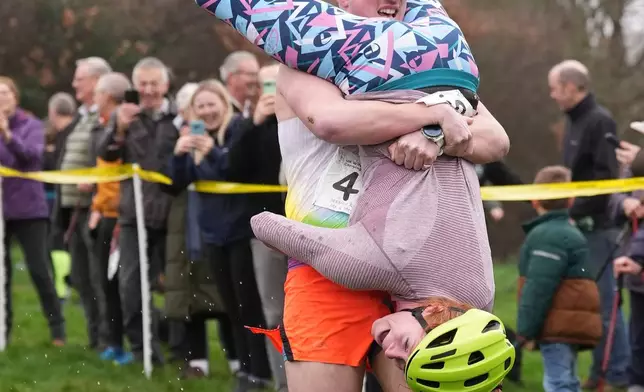 People take part in the annual UK Wife Carrying Race in Dorking, England, Sunday March 8, 2026. (Gareth Fuller/PA via AP)