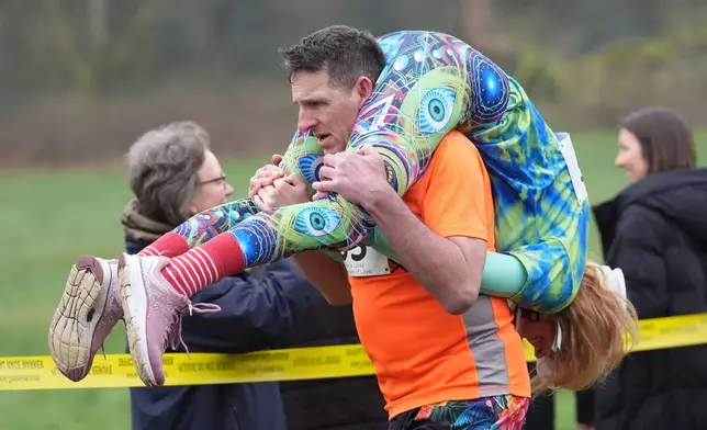 People take part in the annual UK Wife Carrying Race in Dorking, England, Sunday March 8, 2026. (Gareth Fuller/PA via AP)