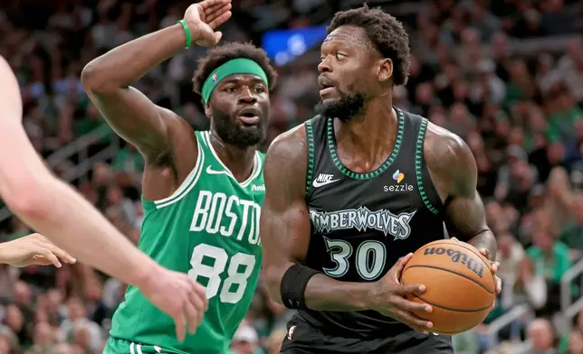 Minnesota Timberwolves forward Julius Randle (30) defends the ball from Boston Celtics center Neemias Queta (88) during the first half of an NBA basketball game, Sunday, March 22, 2026, in Boston. (AP Photo/Mark Stockwell)