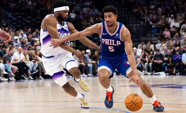 Philadelphia 76ers guard Quentin Grimes (5) dribbles around Utah Jazz guard Elijah Harkless, left, during the first half of an NBA basketball game, Saturday, March 21, 2026, in Salt Lake City. (AP Photo/Anna Fuder)
