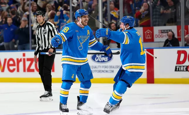 St. Louis Blues' Robert Thomas (18) celebrates with Cam Fowler (17) after scoring during the overtime period of an NHL hockey game against the Edmonton Oilers Friday, March 13, 2026, in St. Louis. (AP Photo/Scott Kane)