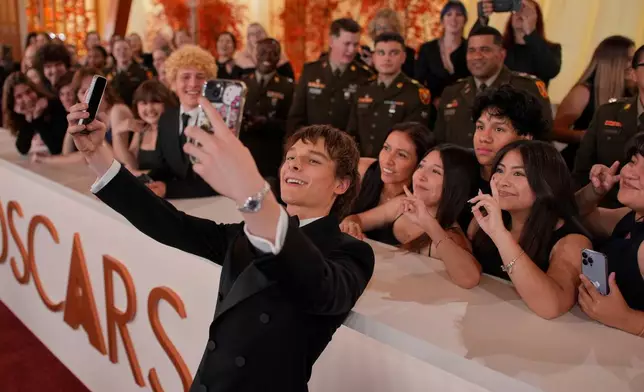 Mason Thames takes selfies with guests as he arrives at the Oscars on Sunday, March 15, 2026, at the Dolby Theatre in Los Angeles. (AP Photo/John Locher)