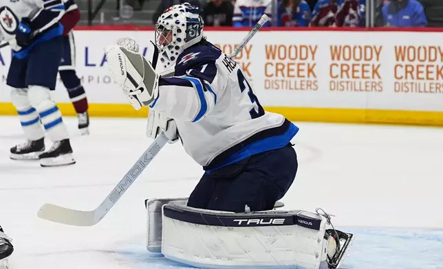 Winnipeg Jets goaltender Connor Hellebuyck makes a glove-save in the first period of an NHL hockey game against the Colorado Avalanche, Saturday, March 28, 2026, in Denver. (AP Photo/David Zalubowski)