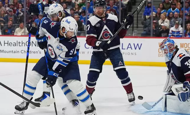 Winnipeg Jets left wing Alex Iafallo (9) shoots the puck past Colorado Avalanche defenseman Brett Kulak (27) as Avalanche goaltender MacKenzie Blackwood, right, makes a stop in the second period of an NHL hockey game Saturday, March 28, 2026, in Denver. (AP Photo/David Zalubowski)