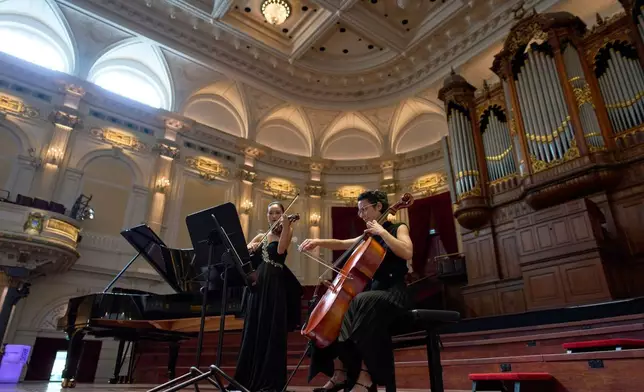 Violinist Hyunjin Cho, left, and cellist Efstratia Chaloulakou perform for students studying with music at Concertgebouw in Amsterdam, Netherlands, on March 5, 2026. (AP Photo/Peter Dejong)