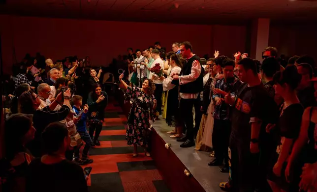 Youngsters stand on the catwalk as relatives take pictures at the end of the SEEN Anonymous Seamstresses Gala, an event organised by the Down Plus Bucharest, an NGO supporting youngsters with Down Syndrome and other intellectual disabilities, in Bucharest, Romania, Wednesday, March 18, 2026, ahead of the World Down Syndrome Day, on March 21. (AP Photo/Andreea Alexandru)