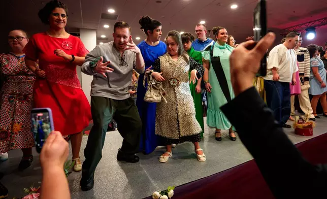 Youngsters dance on the catwalk at the end of the SEEN Anonymous Seamstresses Gala, an event organised by the Down Plus Bucharest, an NGO supporting youngsters with Down Syndrome and other intellectual disabilities, in Bucharest, Romania, Wednesday, March 18, 2026, ahead of the World Down Syndrome Day, on March 21. (AP Photo/Andreea Alexandru)