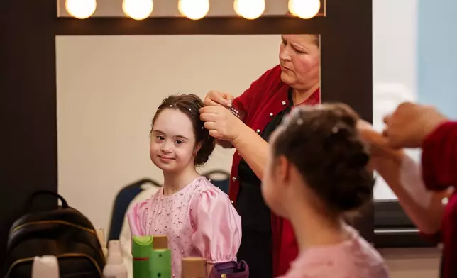 Marusika Burlaca sits while getting her hair done, before the SEEN Anonymous Seamstresses Gala, an event organised by the Down Plus Bucharest, an NGO supporting youngsters with Down Syndrome and other intellectual disabilities, in Bucharest, Romania, Wednesday, March 18, 2026, ahead of the World Down Syndrome Day, on March 21. (AP Photo/ Vadim Ghirda)