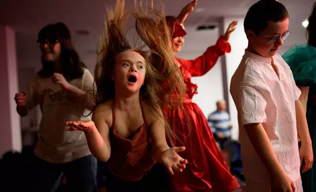 Sophia Lupu, centre, dances on the catwalk at the end of the SEEN Anonymous Seamstresses Gala, an event organised by the Down Plus Bucharest, an NGO supporting youngsters with Down Syndrome and other intellectual disabilities, in Bucharest, Romania, Wednesday, March 18, 2026, ahead of the World Down Syndrome Day, on March 21. (AP Photo/ Vadim Ghirda)
