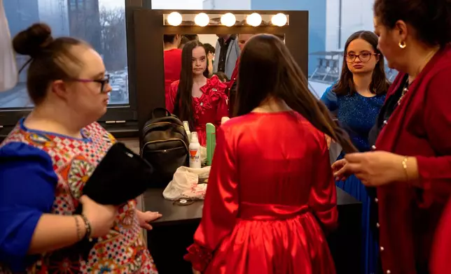 Teodora Brezeanu, looks in the mirror while getting her hair done, before the SEEN Anonymous Seamstresses Gala, an event organised by the Down Plus Bucharest, an NGO supporting youngsters with Down Syndrome and other intellectual disabilities, in Bucharest, Romania, Wednesday, March 18, 2026, ahead of the World Down Syndrome Day, on March 21. (AP Photo/Andreea Alexandru)