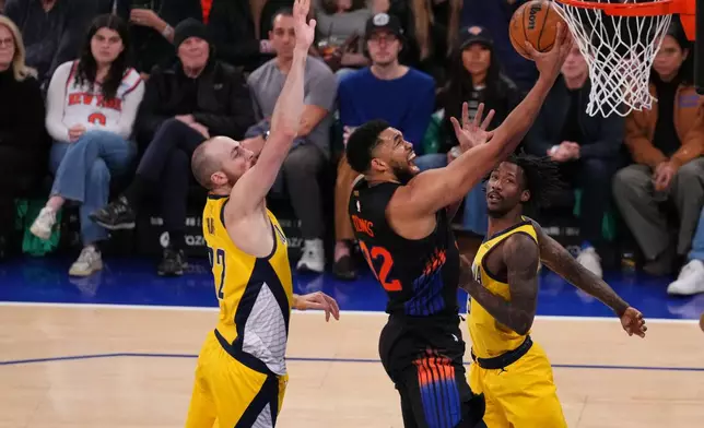 New York Knicks' Karl-Anthony Towns (32) drives past Indiana Pacers' Jay Huff (32) during the second half of an NBA basketball game Tuesday, March 17, 2026, in New York. (AP Photo/Frank Franklin II)