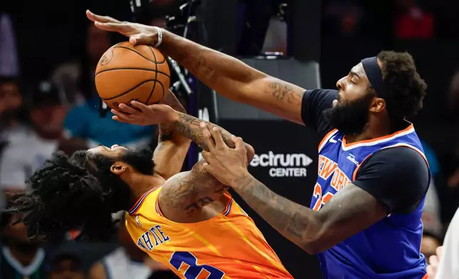 New York Knicks center Mitchell Robinson, right, blocks a shot by Charlotte Hornets guard Coby White during the first half of an NBA basketball game in Charlotte, N.C., Thursday, March 26, 2026. (AP Photo/Nell Redmond)