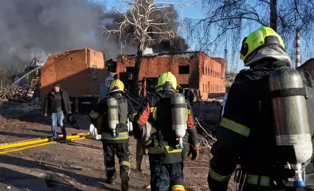 Firefighters approach the damaged railway workshops following a Russia missile and drone attack, in Brovary close to Kyiv, Ukraine, Saturday, March 14, 2026. (AP Photo/Efrem Lukatsky)