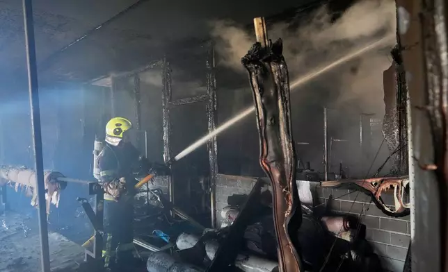 Firefighters put out the fire at a household services centre in a residential neighbourhood, following a Russia missile and drone attack, in Brovary, close to Kyiv, Ukraine, Saturday, March 14, 2026. (AP Photo/Efrem Lukatsky)