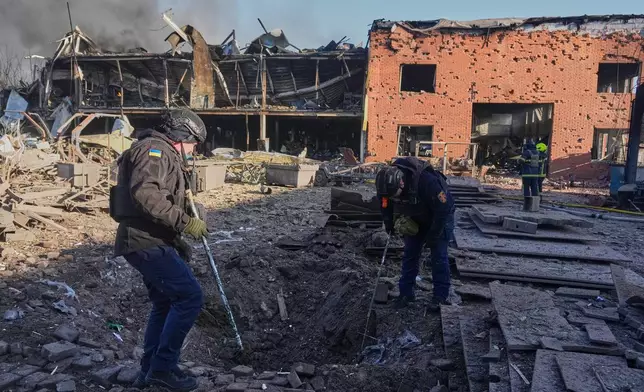 Sappers examine a drone crater at railway workshops following a Russia missile and drone attack, in Brovary close to Kyiv, Ukraine, Saturday, March 14, 2026. (AP Photo/Efrem Lukatsky)