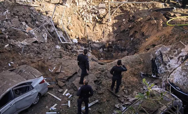 Israeli security forces and rescue teams inspect the site of an Iranian missile strike in Tel Aviv, Israel, Tuesday, March 24, 2026. (AP Photo/Oded Balilty)