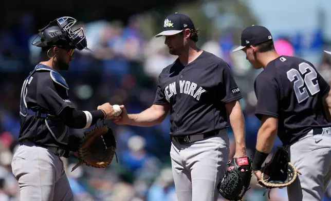 New York Yankees starting pitcher Gerrit Cole, center, gets a fist bump from Yankees catcher J.C. Escarra, left, as Yankees first baseman Ben Rice (22) looks on during the second inning of a spring training baseball game against the Chicago Cubs, Tuesday, March 24, 2026, in Mesa, Ariz. (AP Photo/Ross D. Franklin)