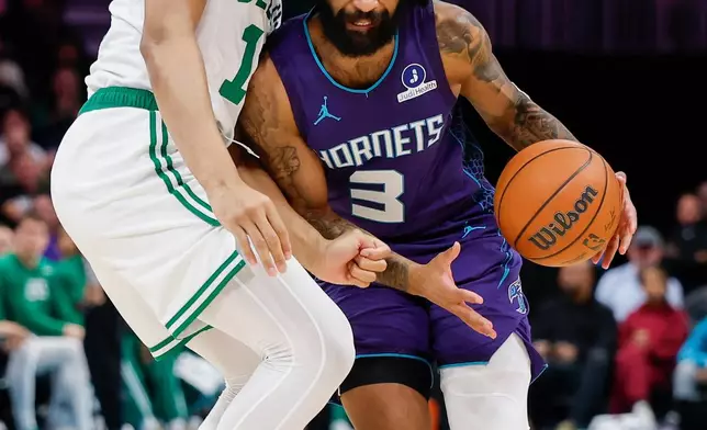 Charlotte Hornets guard Coby White (3) drives into Boston Celtics guard Ron Harper Jr. during the first half of an NBA basketball game in Charlotte, N.C., Sunday, March 29, 2026. (AP Photo/Nell Redmond)
