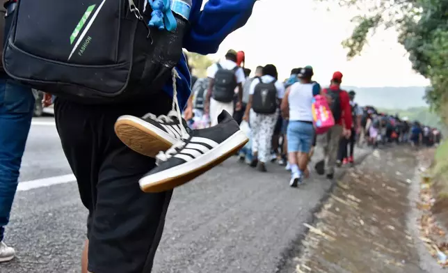 Migrants walk on the highway through the municipality of Huehuetan, Chiapas state, Mexico, Wednesday morning, March 25, 2026, after leaving Tapachula the previous night. (AP Photo/Edgar H. Clemente)