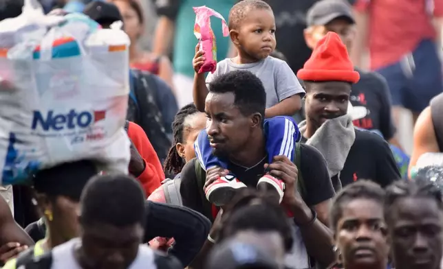 Migrants walk on the highway through the municipality of Huehuetan, Chiapas state, Mexico, Wednesday, March 25, 2026, after leaving Tapachula the previous night. (AP Photo/Edgar H. Clemente)