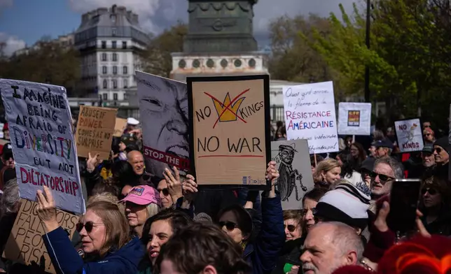 A woman holding a banner reading "No Kings, No War" takes part in the "No Kings" protest in Paris, France, Saturday, March 28, 2026. (AP Photo/Aurelien Morissard)