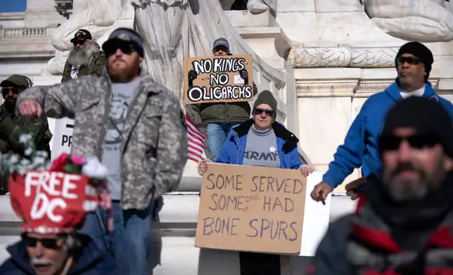 FILE - A person holds a sign reading "No Kings, No Oligarchs" as veterans and their supporters demonstrate outside Union Station Nov. 11, 2025, in Washington. (AP Photo/Mark Schiefelbein, File)