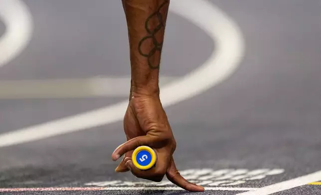 Elija Godwin, of United States, hold a baton prior to the start of a men's 4 X 400 meters relay heat at the World Athletics Indoor Championships in Torun, Poland, Sunday, March 22, 2026. (AP Photo/Petr David Josek)