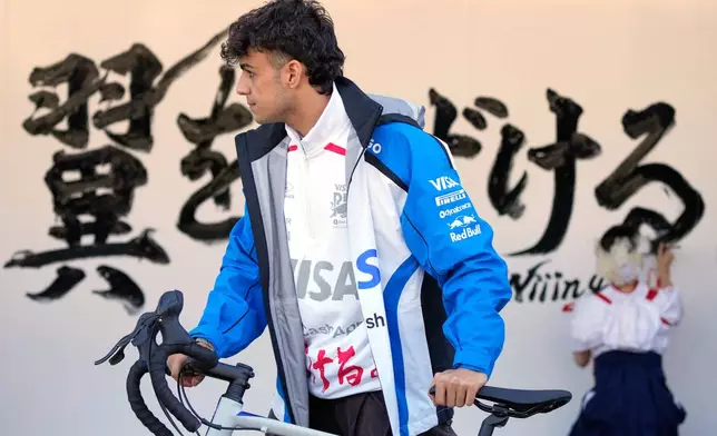 Racing Bulls driver Arvid Lindblad of Britain rides a bicycle ahead of the Japanese Formula One Grand Prix Thursday, March 26, 2026, in Suzuka, Central Japan. (AP Photo/Eugene Hoshiko)