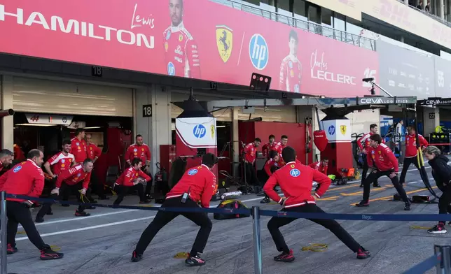 Ferrari mechanics stretch in front of the garage in Suzuka, central Japan, Thursday, March 26, 2026, ahead of Sunday's Japanese Formula One Grand Prix race. (AP Photo/Hiro Komae)