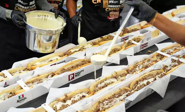 Volunteers assemble cheesesteaks in a Guinness World Record attempt on National Cheesesteak Day at Philadelphia International Airport, Tuesday, March 24, 2026, in Philadelphia. (AP Photo/Matt Rourke)