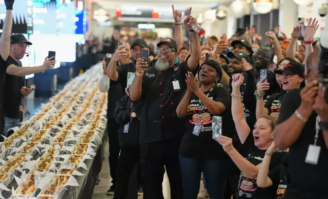 Volunteers cheer as the results of their Guinness World Record was announced on National Cheesesteak Day at Philadelphia International Airport, Tuesday, March 24, 2026, in Philadelphia. (AP Photo/Matt Rourke)
