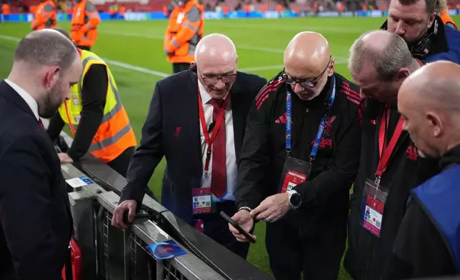 Officials inspect advertising hoarding after Galatasaray player Noa Lang slices finger after colliding during the second leg of the Champions League round of 16 soccer match between Liverpool and Galatasaray, in Liverpool, England, Wednesday, March 18, 2026. (AP Photo/Jon Super)