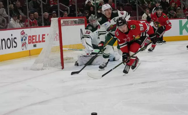 Chicago Blackhawks center Connor Bedard (98) and Minnesota Wild defenseman Jared Spurgeon (46) skate for the puck during the first period of an NHL hockey game, Tuesday, March, 17, 2026, in Chicago. (AP Photo/David Banks)