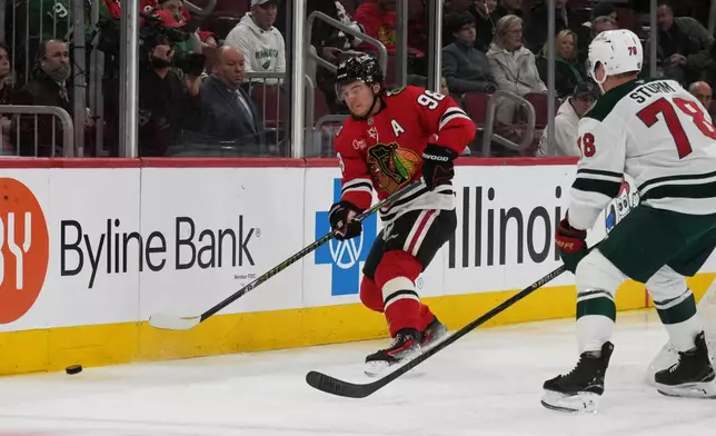 Chicago Blackhawks center Connor Bedard (98) and Minnesota Wild center Nico Sturm (78) go for the puck during the first period of an NHL hockey game Tuesday, March, 17, 2026, in Chicago. (AP Photo/David Banks)