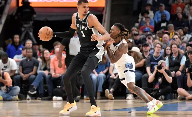 San Antonio Spurs forward Victor Wembanyama (1) handles the ball against Memphis Grizzlies guard Javon Small, right, in the first half of an NBA basketball game Wednesday, March 25, 2026, in Memphis, Tenn. (AP Photo/Brandon Dill)