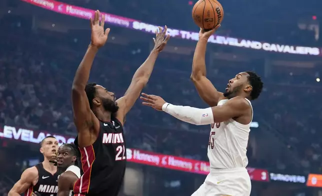 Cleveland Cavaliers guard Donovan Mitchell, right, shoots over Miami Heat forward Andrew Wiggins (22) in the first half of an NBA basketball game in Cleveland, Wednesday, March 25, 2026. (AP Photo/Sue Ogrocki)
