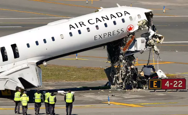 Aircraft maintenance workers arrive to inspect the wreckage of an Air Canada Express jet, Tuesday, March 24, 2026, just off the runway where it had collided with a Port Authority fire truck Sunday night at LaGuardia Airport in New York. (AP Photo/Yuki Iwamura)