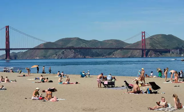 People lounge in the sand at Crissy Field East Beach backdropped by the Golden Gate Bridge in San Francisco, Tuesday, March 17, 2026. (AP Photo/Godofredo A. Vásquez)