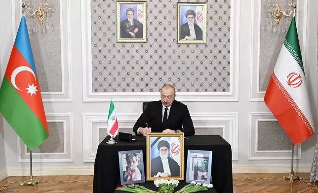 In this photo provided by Azerbaijan's Presidential Press Service, Azebaijan's President Ilham Aliyev writes a message in a condolence book for the late Iranian Supreme Leader Ayatollah Ali Khamenei at the Iranian Embassy in Baku, Azerbaijan, Wednesday, March 4, 2026. (Azerbaijan's Presidential Press Service via AP)