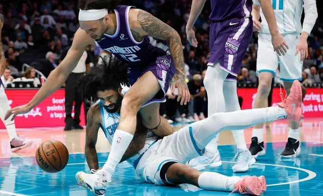 Sacramento Kings guard Devin Carter (22) falls over Charlotte Hornets guard Coby White for the ball during the first half of an NBA basketball game in Charlotte, N.C., Tuesday, March 24, 2026. (AP Photo/Nell Redmond)