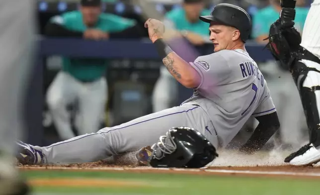 Colorado Rockies' TJ Rumfield (7) scores on a double hit by Jordan Beck during the first inning of a baseball game against the Miami Marlins, Sunday, March 29, 2026, in Miami. (AP Photo/Lynne Sladky)