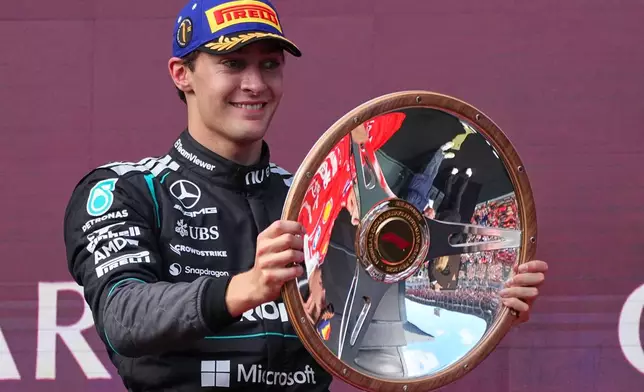 Mercedes driver George Russell of Britain celebrates on the podium with his trophy after winning the Australian Formula One Grand Prix at Albert Park, in Melbourne, Australia, Sunday, March 8, 2026. (AP Photo/Scott Barbour)