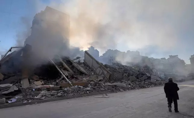 A man passes in front of a destroyed building that housed a branch of Al-Qard Al-Hassan, a non-bank financial institution run by Hezbollah, which was hit by an Israeli airstrike in Dahiyeh, Beirut's southern suburbs, Lebanon, Tuesday, March 10, 2026. (AP Photo/Hussein Malla)