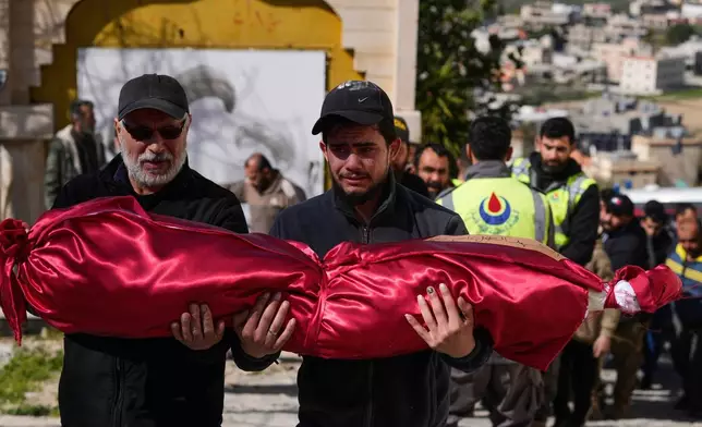 A man, left, carries the body of his son, Kassem Younis, who was killed in an Israeli airstrike, during his funeral procession in the southern village of Chehabiyeh, Lebanon, Wednesday, March 11, 2026. (AP Photo/Mohammed Zaatari)