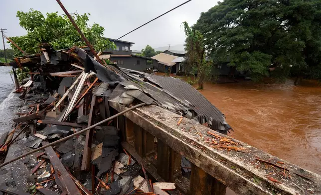 Debris from a storm-damaged house sits against a bridge along Kaukonahua Stream, caused by flooding from severe rains in Waialua, Hawaii, Friday, March 20, 2026. (AP Photo/Mengshin Lin)