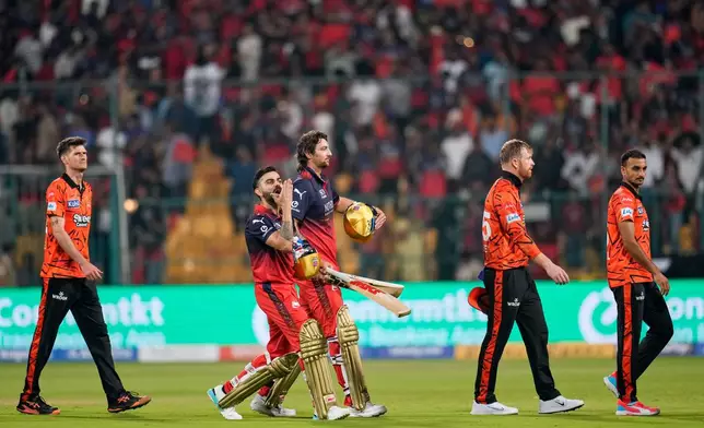 Royal Challengers Bengaluru's Virat Kohli, second left, gestures to the fans as he walks out with teammate Tim David after winning the Indian Premier League cricket match against Sunrisers Hyderabad in Bengaluru, India, Saturday, March 28, 2026. (AP Photo/Aijaz Rahi)