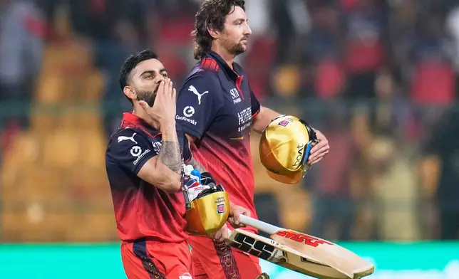 Royal Challengers Bengaluru's Virat Kohli, left, gestures to the fans as he walks out with teammate Tim David after winning the Indian Premier League cricket match against Sunrisers Hyderabad in Bengaluru, India, Saturday, March 28, 2026. (AP Photo/Aijaz Rahi)