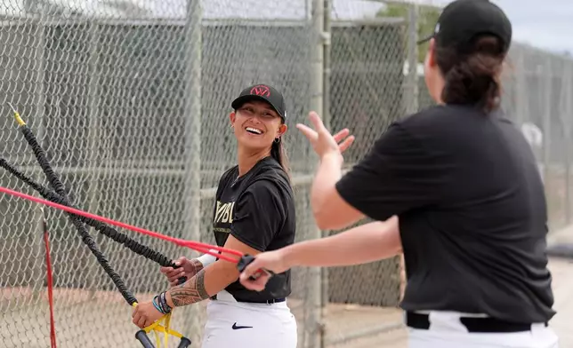 Kelsie Whitmore talks with another player as they use resistance bands during a Women's Pro Baseball League (WPBL) practice, Wednesday, March 18, 2026, in Fort Myers, Fla. (AP Photo/Rebecca Blackwell)