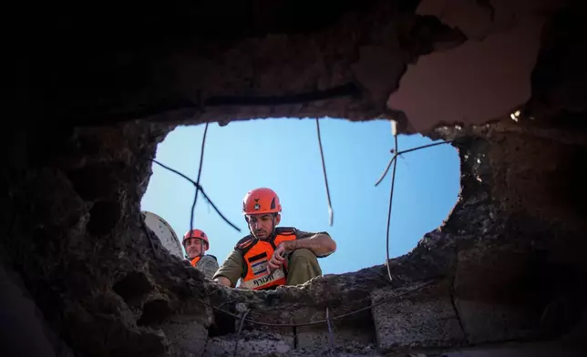 Officers from Israel's Home Front Command inspect a damaged apartment building after an Iranian missile strike in Petah Tikva, Israel, Tuesday, March 3, 2026. (AP Photo/Ohad Zwigenberg)